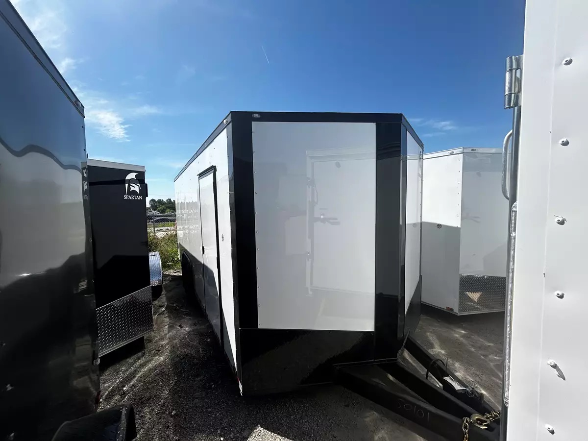 Multiple white enclosed cargo trailers with black trim in a staging area